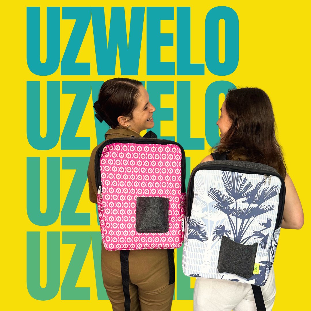Zwei Frauen stehen Rücken an Rücken und tragen Rucksäcke von UZWELO, einer mit pinkem Muster und die andere mit floralem Design.