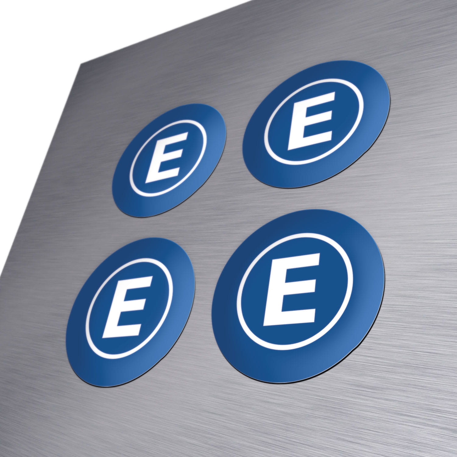 Vier runde, bedruckte Magnete in Blau mit einem weißen E im Kreis, auf einer metallischen Oberfläche.