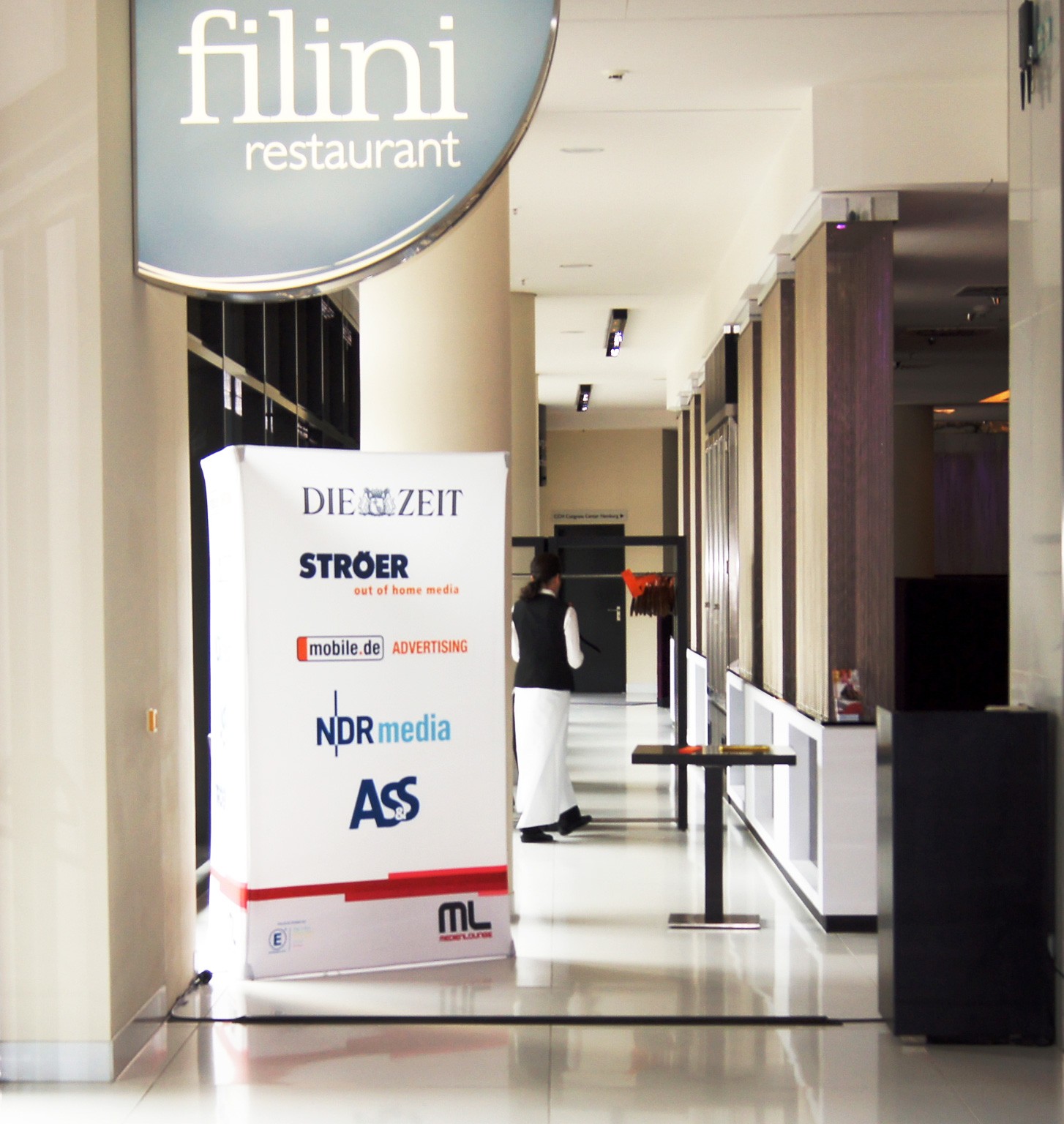 Werbesäule mit Werbung für 'DIE ZEIT', 'mobile.de', 'NDR media' und 'STROER' vor dem Restaurant filini.