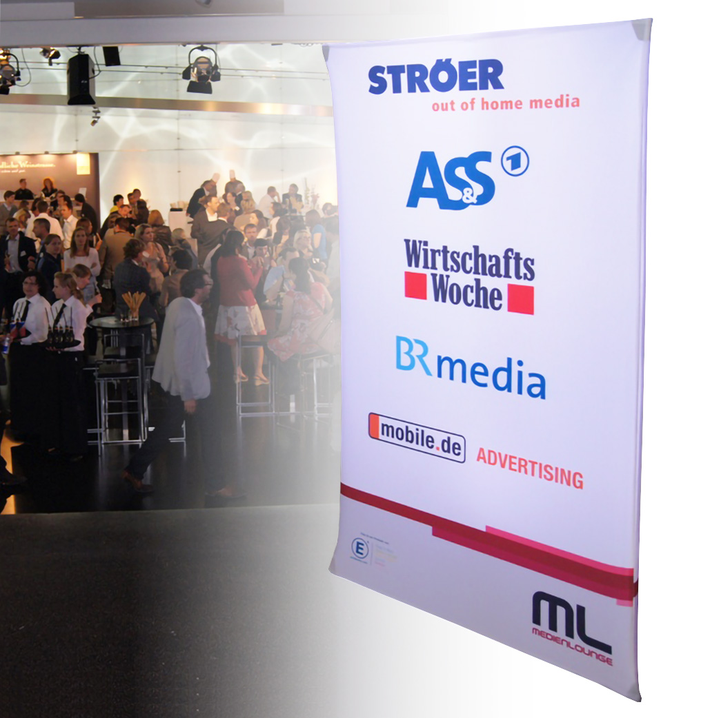 Werbesäule mit Logos von Ströer, ASS, WirtschaftsWoche, BR media und mobile.de, im Hintergrund eine Veranstaltung mit Publikum.