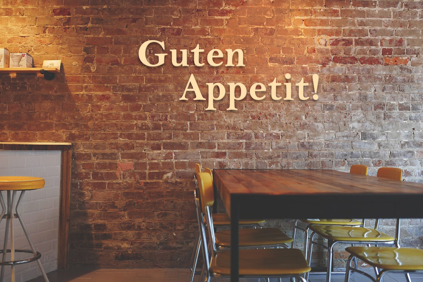 Holzwand mit Fräsbuchstaben, die 'Guten Appetit!' sagen, in einem Restaurant.