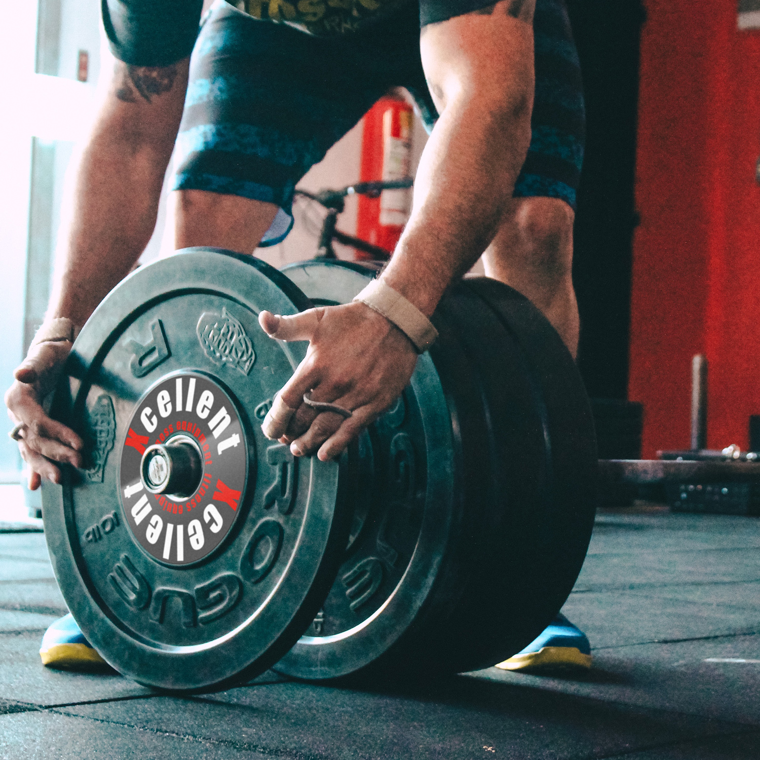 Ein Mann hebt eine schwere Hantel im Fitnessstudio, die mit einer stoßfesten Folie geschützt ist.