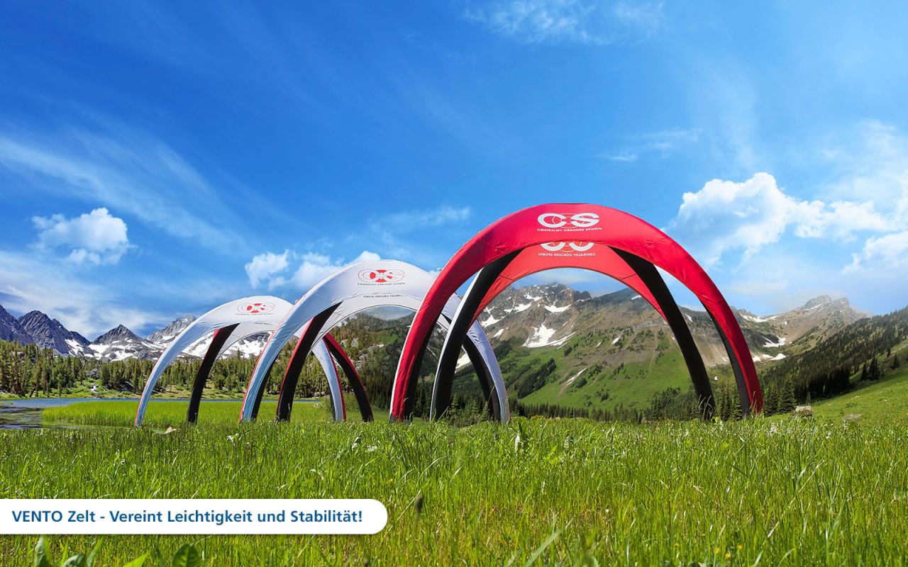 Drei aufblasbare Zelte in rot und grau auf einer grünen Wiese vor einer Berglandschaft, Produkt 'Vento Aufblasbares Zelt Cos 1280X1280'.