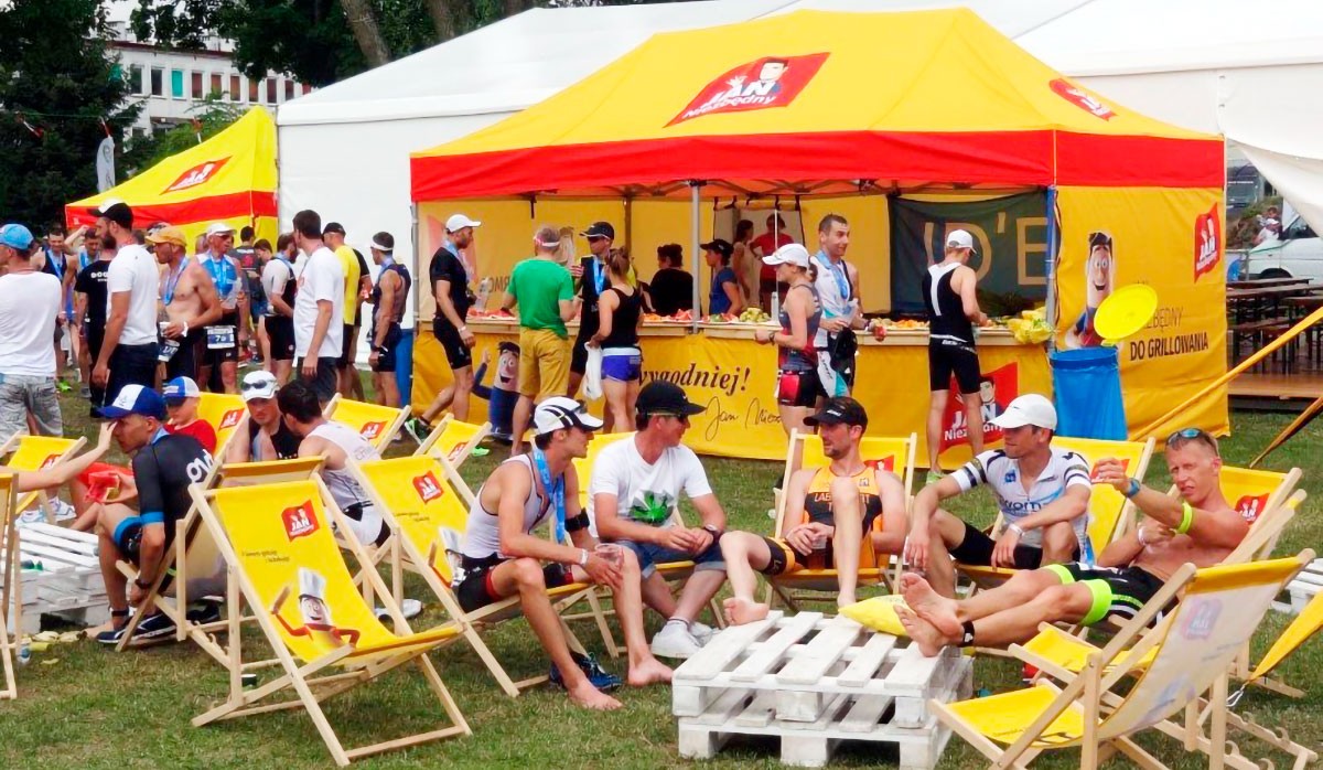 Faltzelt 3x6m von ENTDECKER bei einem Sommerfest, mit Gästen in Sportkleidung und Liegestühlen.