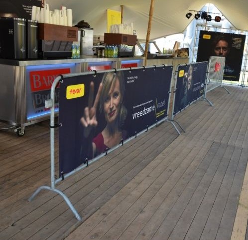 Absperrgitter von ENTDECKER mit Werbebanner, auf einem Holzfußboden in einem Veranstaltungsbereich.