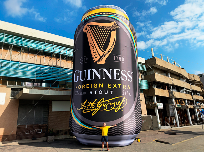 Aufblasbare Werbung in Form einer großen Guiness-Bierdose, Person steht davor.