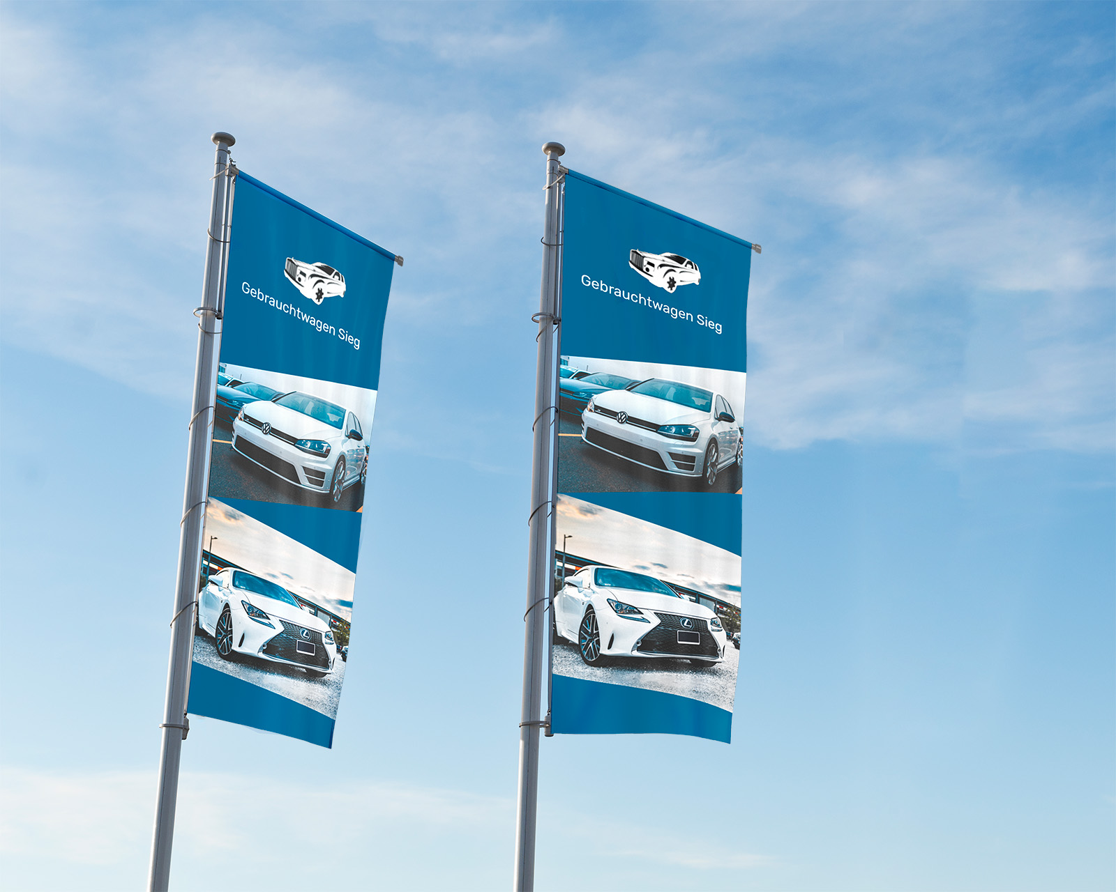 Zwei Hissfahnen mit Bildern von Gebrauchtwagen und dem Text 'Gebrauchtwagen Güng' vor blauem Himmel.