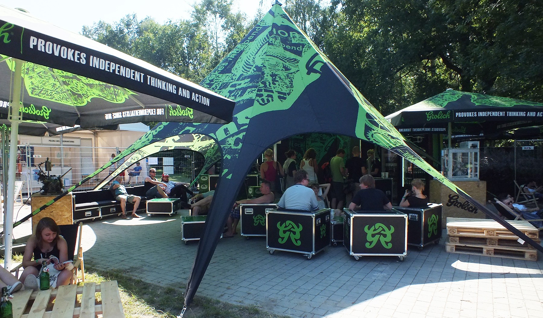 Sternzelt Jh Static Base von Grolsch, mit grünem Design, umgeben von Menschen, die sich im Freien aufhalten.