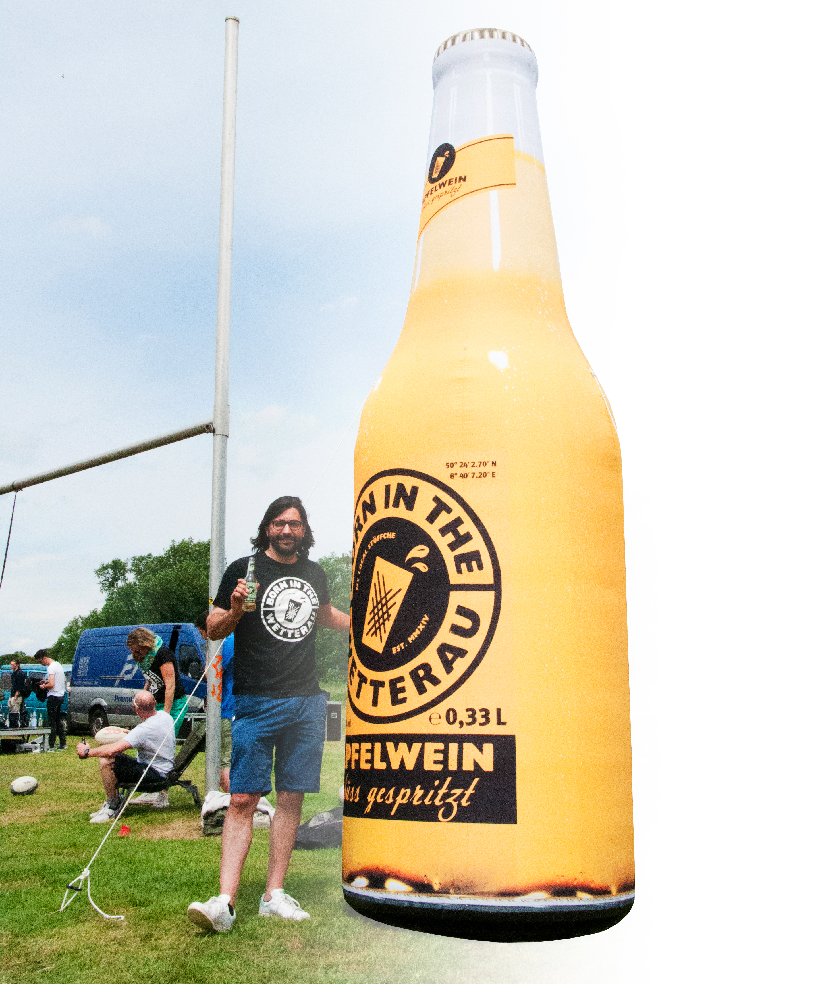 Mann steht neben einer übergroßen Flasche des Produkts 'Blow Up Easy Inflate Ad Flasche Born In The Wetterau', die Apfelwein bewirbt.