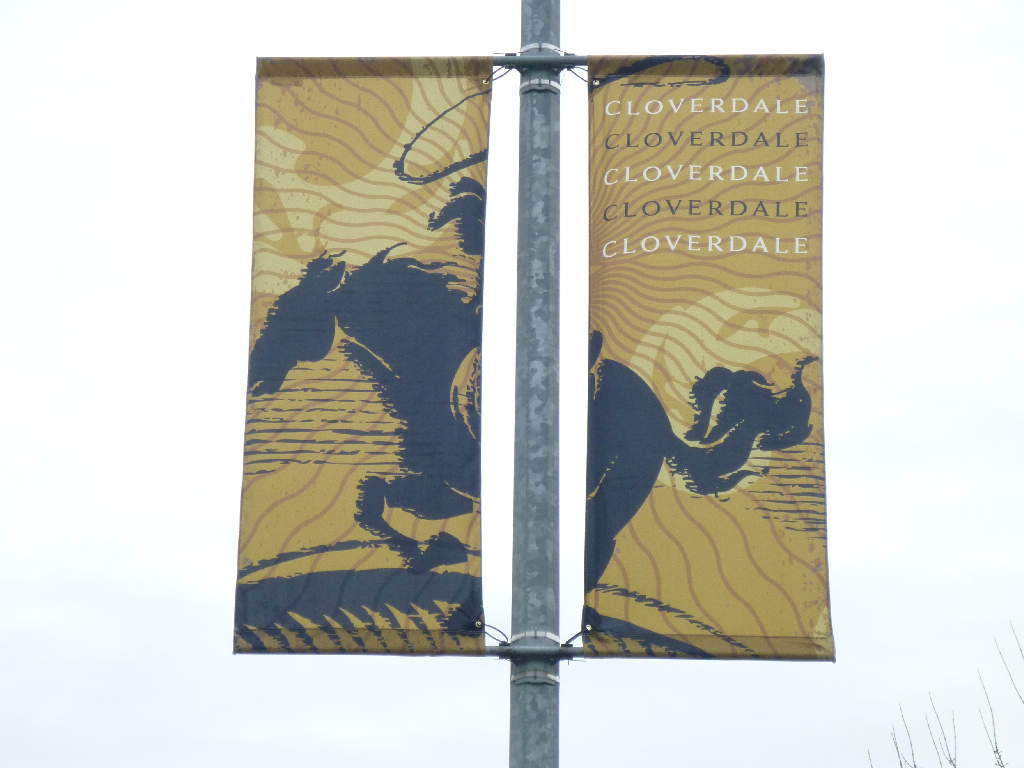 Banner mit dem Schriftzug 'CLOVERDALE' und einem Reiter auf einem Pferd, in gelb und braun gehalten.
