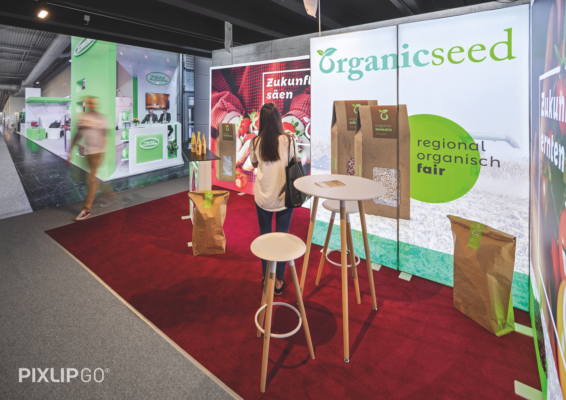 Messestand von Pixlip Go mit dem Branding organicseed, zeigt regionale, biologische Produkte. Eine Person steht an einem Tisch.