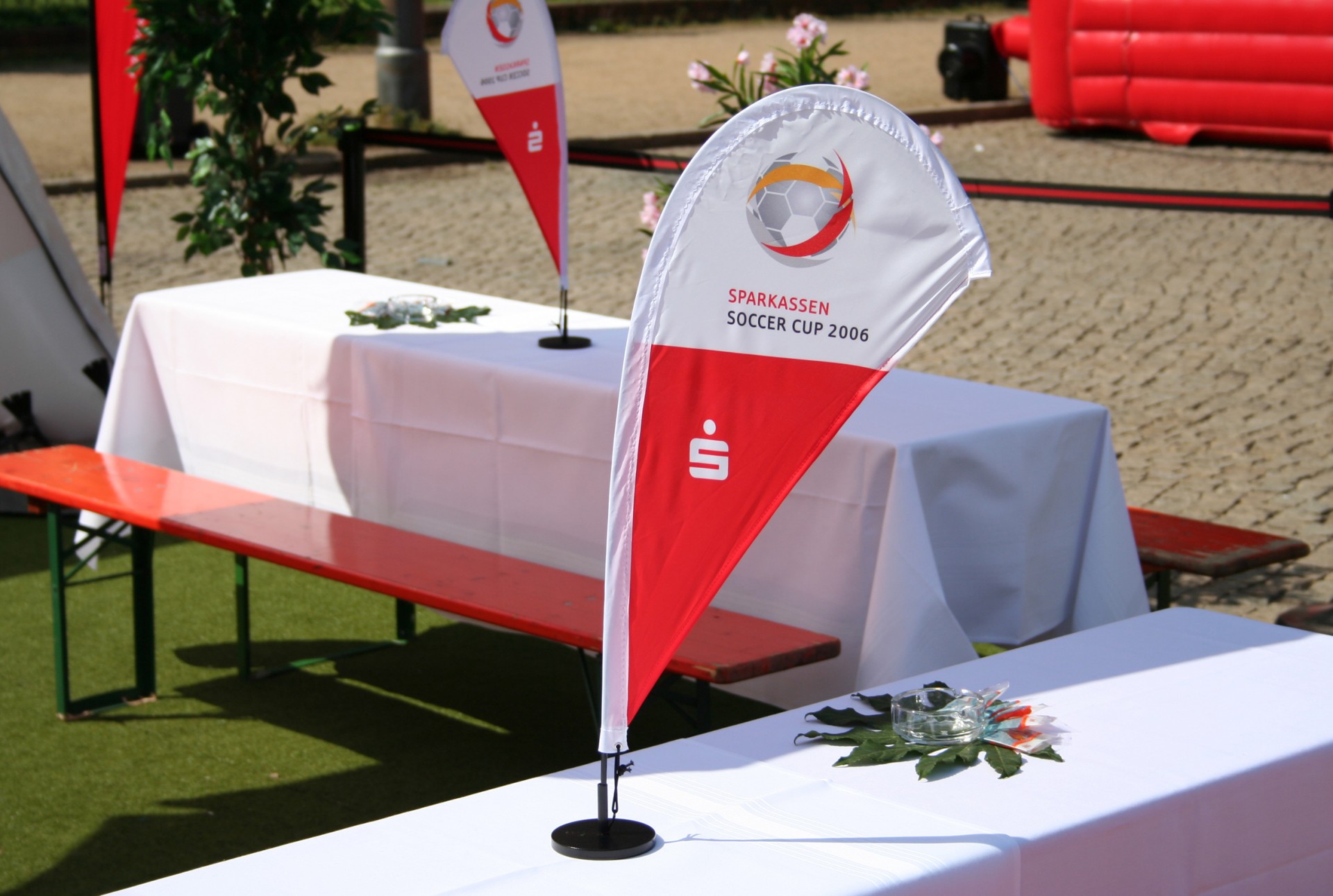 Tischaufsteller 'Easyflag Micro' für den Sparkassen Soccer Cup 2006, rot-weiße Fahne mit Fußballmotiv auf einem Tisch.