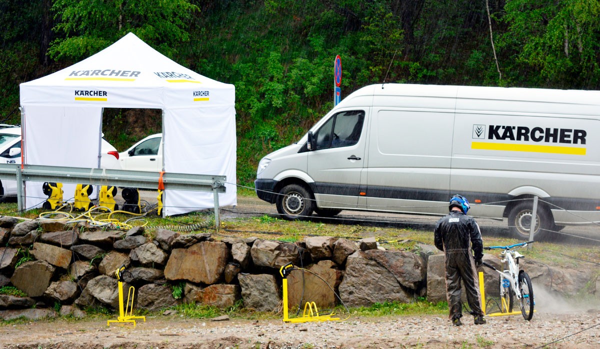 Faltzelt Octa 3x3 von Kärcher, aufgestellt neben einem Kärcher-Fahrzeug, mit einer Person, die ein Fahrrad reinigt.