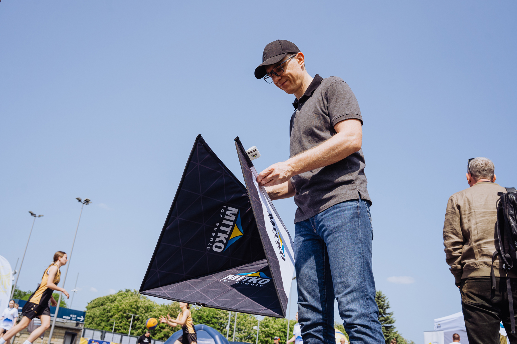 Faltbarer Aufsteller Pyramide in zusammengeklapptem Zustand, dreieckige Form, weiße Oberfläche mit schwarzem Rand.