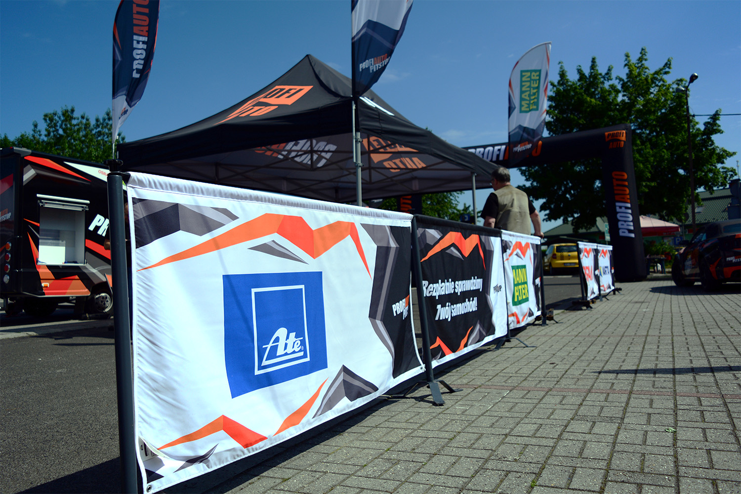 Zelt mit Werbebannern für die Rennsportbande Reihe und ATE, im Freien auf einem Event.