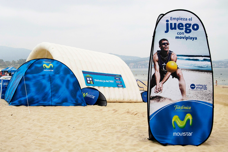 Werbebanner für 'Quicktower Strand' mit einem Mann, der einen Ball am Strand spielt, im Hintergrund ein Zelt und das Meer.