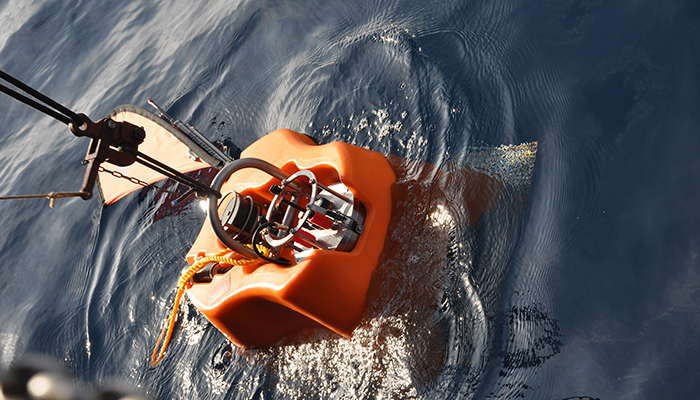 Kum Einsatz, ein orangefarbenes Unterwassergerät, das im Wasser schwimmt, mit einem Haltegriff und technischen Komponenten.