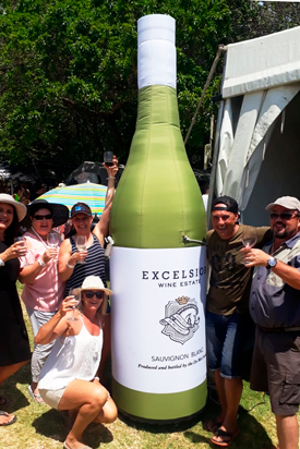 Gruppe von Menschen posiert mit einer übergroßen Flasche des Produkts 'Kleine Flasche' von Excelsior Wine Estate.