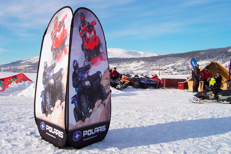 Zelt mit Werbung für den Produkt 'Quicktower Winter' von Polaris, umgeben von Schneemobilen auf einer verschneiten Landschaft.