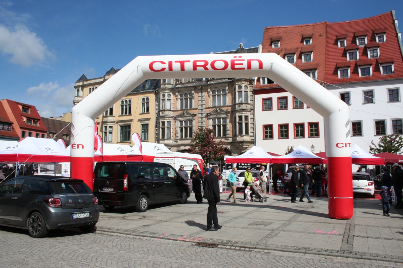 Aufblasbarer Torbogen von ENTDECKER mit der Aufschrift 'CITROËN', auf einem Platz mit Menschen und Fahrzeugen.