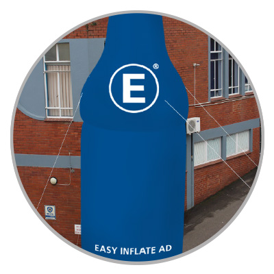 Blaues Werbebanner in Flaschenform mit dem Text 'EASY INFLATE AD' und einem großen weißen 'E' darauf, befestigt an einem Gebäude.