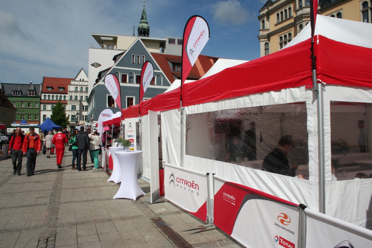 Zeltstadt Eventzelt Easydome Xp mit roten und weißen Markisen, beschriftet mit Citroën und anderen Logos, auf einem Platz mit Besuchern.
