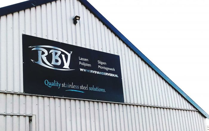 Werbeschild für RBY mit dem Slogan 'Quality stainless steel solutions' an einer Wand.