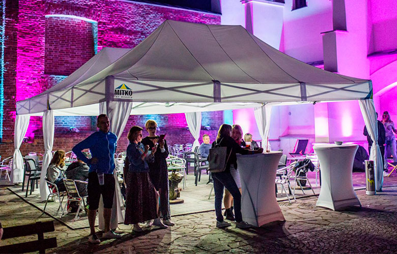 Veranstaltung mit dem Produkt 'Octa Pro LED', Zelt mit Beleuchtung, Gäste stehen um Stehtische.