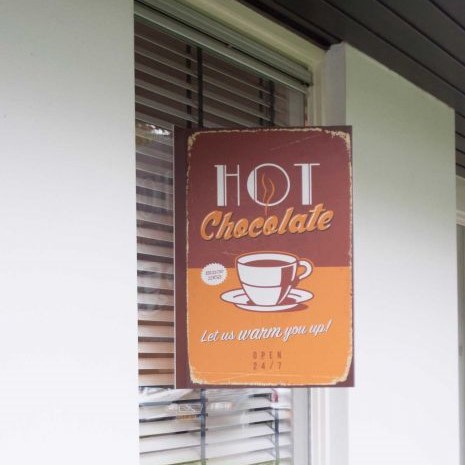 Maklerschild für ein Café mit der Aufschrift 'HOT Chocolate' und dem Slogan 'Let us warm you up!'