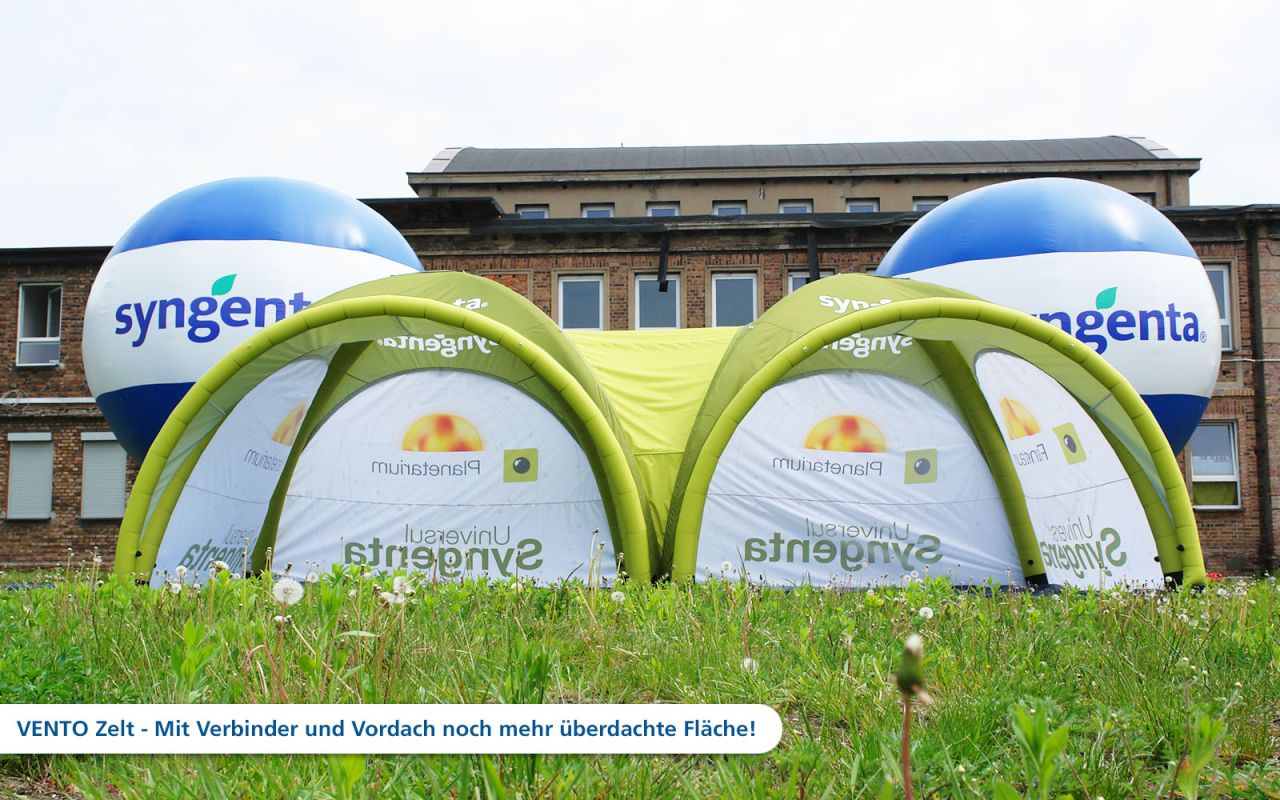 Aufblasbares Zelt 'Vento' von Syngenta mit zwei großen, blauen Ballons und grüner Überdachung auf einer Wiese.
