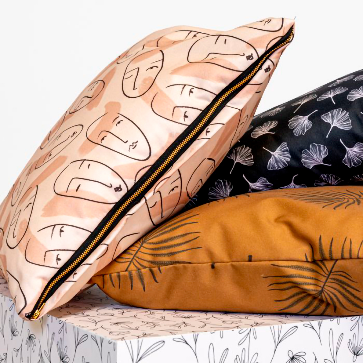 Dekokissen mit verschiedenen Designs: ein Kissen mit bunten Kreisen, ein Kissen mit floralen Motiven, ein Kissen mit grafischem Muster und ein unifarbenes Kissen.
