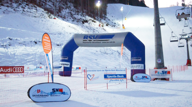 Startbogen des Skirennens mit Sponsorenlogos und Schnee im Hintergrund.
