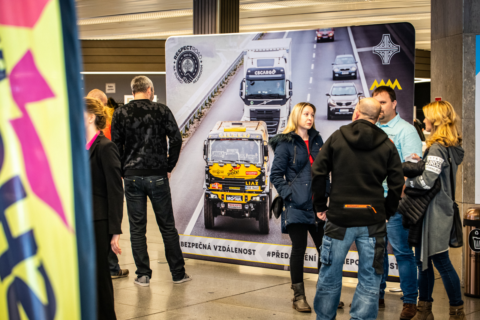 Messestand mit dem Produkt 'Zipper Wall', Personen stehen vor einem großen Banner mit einem Lkw auf einer Straße.